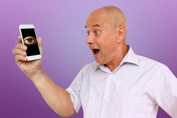 Lustiger Mann im hellen Hemd mit albernem Blick, der den Mund zum Smartphone öffnet, ein Auge schaut aus dem Telefon, Technologiekonzept, waagerecht, Nahaufnahme, Kopierraum — Stockfoto