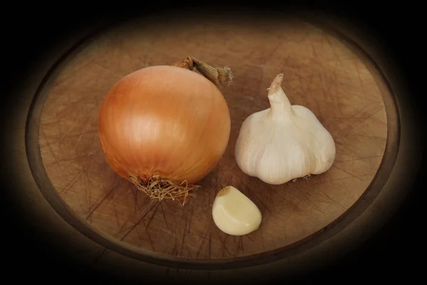 Zwiebeln, Knoblauch auf einem hölzernen runden Brett, Gemüsekonzept gegen Erkältungen, waagerecht, Nahaufnahme, Kopierraum — Stockfoto
