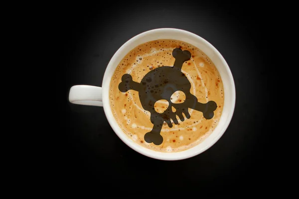 Fehér széles csésze kávé, koponya alakú cappuccino fekete háttérben matrica, felülnézet, helytakarékos, közelről, veszély koncepció — Stock Fotó