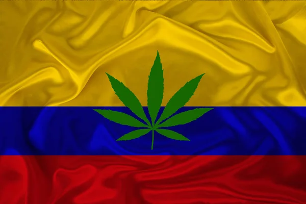 Green leaf of hemp and the beautiful silk national flag of Colombia, the concept of medical cannabis, legalization of drugs, drug trafficking offenses — Stock Photo, Image