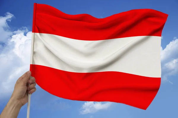 Mężczyzna trzyma rękę na tle nieba z chmur flagi narodowej Austrii na luksusową satynową teksturę, jedwabiu z falami, zbliżenie, przestrzeń kopiowania — Zdjęcie stockowe