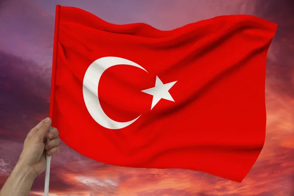 Männliche Hand hält vor dem Hintergrund des Himmels mit Wolken die Nationalflagge der Türkei auf einer luxuriösen Textur aus Satin, Seide mit Wellen, Nahaufnahme, Kopierraum, Reisekonzept, Wirtschaft, Politik — Stockfoto