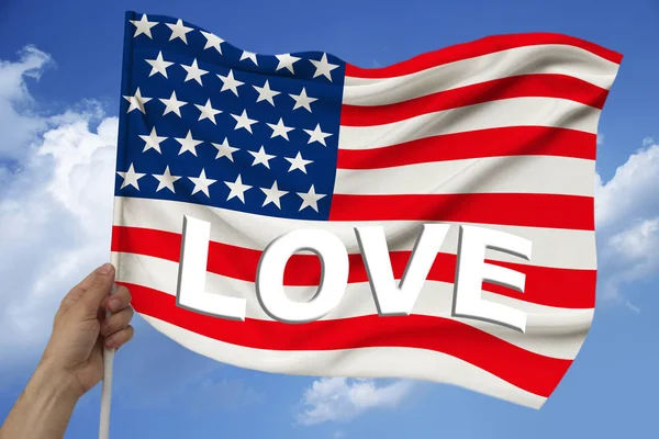Ręka trzyma na tle nieba z chmur kolorowe flagi USA na luksusową fakturę satyny, jedwabiu z falami, zbliżenie, przestrzeń kopiowania — Zdjęcie stockowe