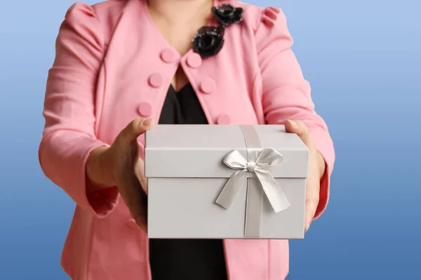 woman gives a present in a light gray box with a satin ribbon and bow, concept of valentines day, christmas presents, mother\'s day, new year, close-up, copy space