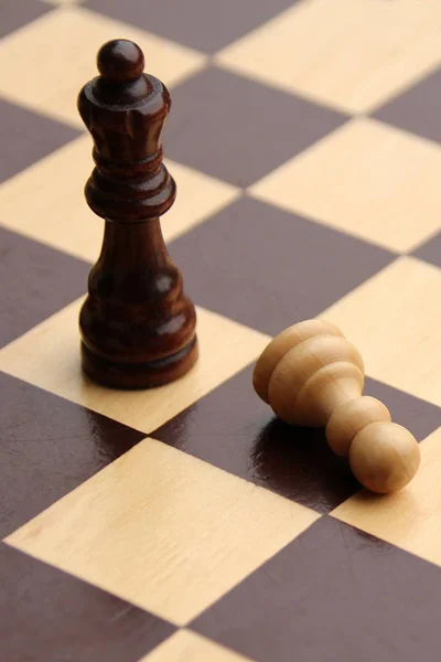 Королева деревянных шахматных фигур и лежащая пешка на доске, корпоративная концепция — стоковое фото