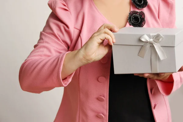 Femme tenant un cadeau dans une boîte gris clair avec un ruban de satin et un arc, concept de Saint-Valentin, cadeaux de Noël, fête des mères, nouvel an, gros plan, espace de copie — Photo