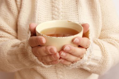 bir kadının elinde sıcak kokulu çay fincan, örme kazak doku, yakın çekim, kopya alanı, kış veya sonbahar ruh kavramı