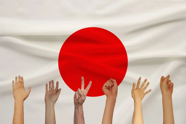 Muchas manos levantadas de la gente en el fondo de una bandera de seda de color del estado con pliegues suaves, concepto de unidad de la gente — Foto de Stock