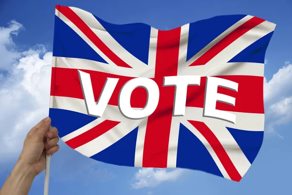 Hand holds against the background of the sky with clouds the colored flag of Great Britain on a luxurious texture of satin, silk with waves, closeup, copy space — Stock Photo, Image