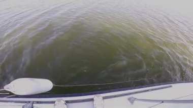 Baltık Denizi 'nde yelken açan küçük beyaz bir yat. Kıç tarafından dalgalar savruluyor. Seyahat konsepti, deniz balıkçılığı.