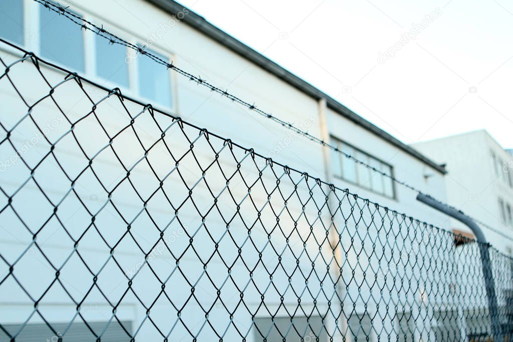 wire mesh, barbed wire fence on top, concept prison, security zone, close-up, copy space