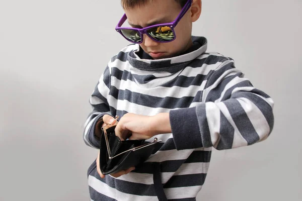 Chłopiec w ciemnych okularach przeciwsłonecznych, w swetrze w paski, wyciąga papierowe banknoty Eu, przestrzeń do kopiowania, fioletowe tło, zbliżenie — Zdjęcie stockowe