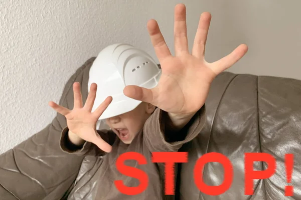 Boy, child with a white protective helmet on his head closes his hands, the concept of mobbing, gaslighting, psychological and physical violence, humiliation, close-up, selective focus, the word STOP — Stock Photo, Image