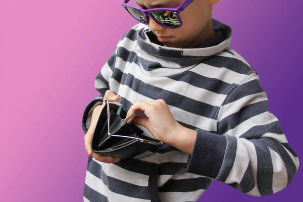 Boy in dark sunglasses, in a striped sweater, takes out paper notes of the EU banknotes, copy space, purple background, close-up — Stock Photo, Image