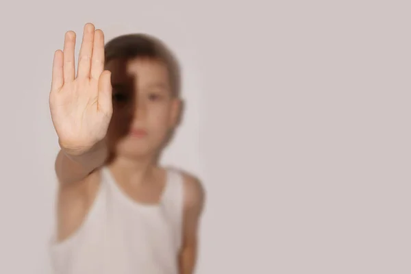 Un niño con una camiseta blanca se para, cierra la palma de su mano, el concepto de protesta, primer plano — Foto de Stock