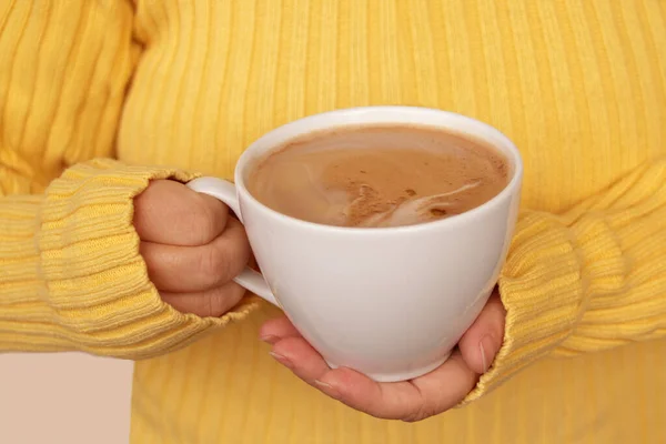 Taza de cacao con leche o capuchino en las manos de una niña en un suéter amarillo, el concepto de estado de ánimo de otoño, primer plano — Foto de Stock