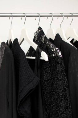 Askılarda siyah renkli kadın kıyafetleri, moda, yas ve alışveriş için bir konsept, dikey