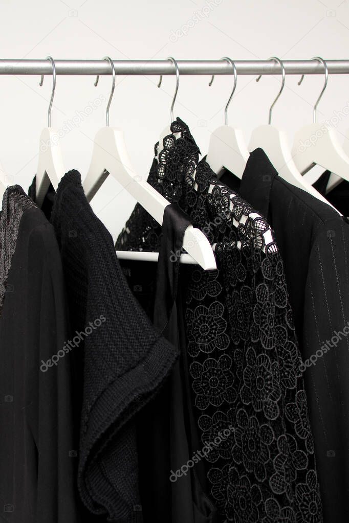 set of women's clothing in black in different colors on hangers, a concept for fashion, mourning and shopping, vertical