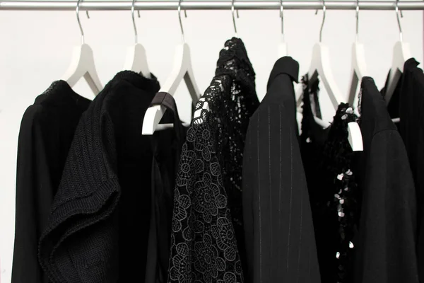 Conjunto de roupas femininas em preto em cores diferentes em cabides, um conceito para moda, luto e compras — Fotografia de Stock