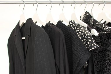 Askılarda siyah renkli kadın kıyafetleri, moda, yas ve alışveriş için bir konsept.