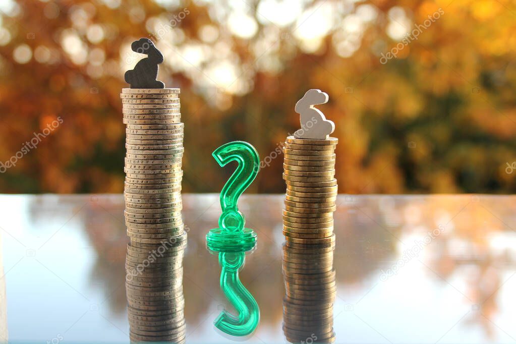 coins stack of cash of the European Union with a model of colored bunnies on a blurred background autumn landscape in the backlight, the concept of a white, gray and black salary