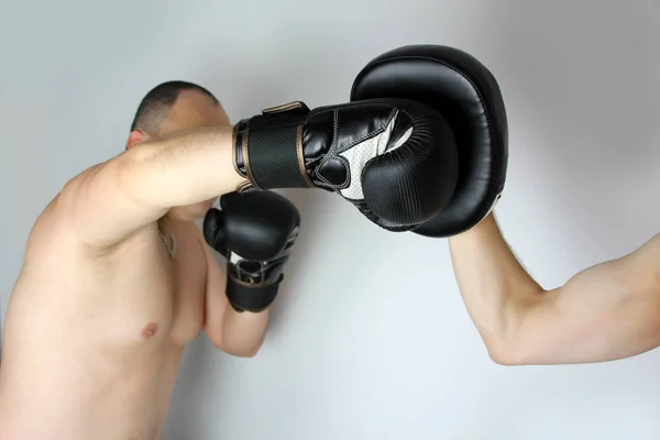 Treinamento de um boxeador em uma luva de boxe preto, praticando um chute com um parceiro, close-up, espaço de cópia, conceito de esportes — Fotografia de Stock