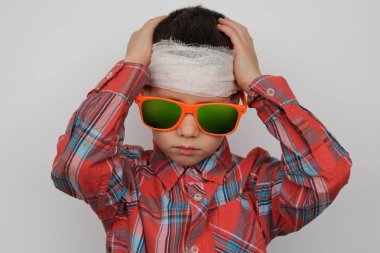 boy in dark sunglasses, in a plaid shirt, his head is bandaged, holding his head, medical concept, close-up clipart