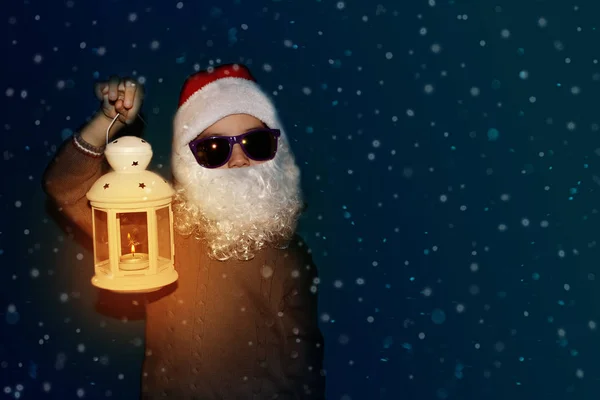 Niño con una barba blanca en un traje de Santa Claus o luces elfos con una linterna en la mano, concepto de Navidad — Foto de Stock