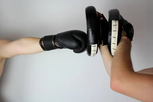 Treinamento de um boxeador em uma luva de boxe preto, praticando um chute com um parceiro, close-up, espaço de cópia, conceito de esportes — Fotografia de Stock