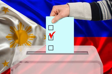 Erkek seçmen, Filipinler ulusal bayrağı, devlet seçimleri konsepti ve referandumun arka planına karşı şeffaf bir sandık içinde oy kullanıyor.