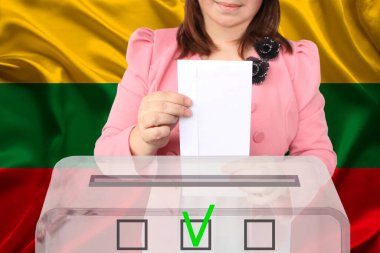 Kadın seçmen oy pusulasını Litvanya ulusal bayrağı, devlet seçimleri konsepti ve referandumun arka planında şeffaf bir oy sandığına bırakıyor.