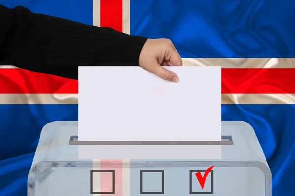 woman voter lowers the ballot in a transparent ballot box against the background of the iceland national flag, concept of state elections, referendum