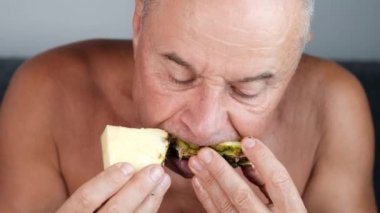 Bronzlaşmış yaşlı adam iştah açıcı bir şekilde olgun sarı bir ananas yiyor, vejetaryen yemek konsepti, egzotik ülkelerde rahatlama.