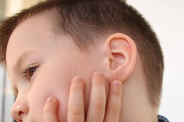 Küçük çocuk kulağına tutunuyor, yüzünün bir kısmı, tıbbi konsept, işitme kontrolü, orta kulak iltihabı, otitis medya