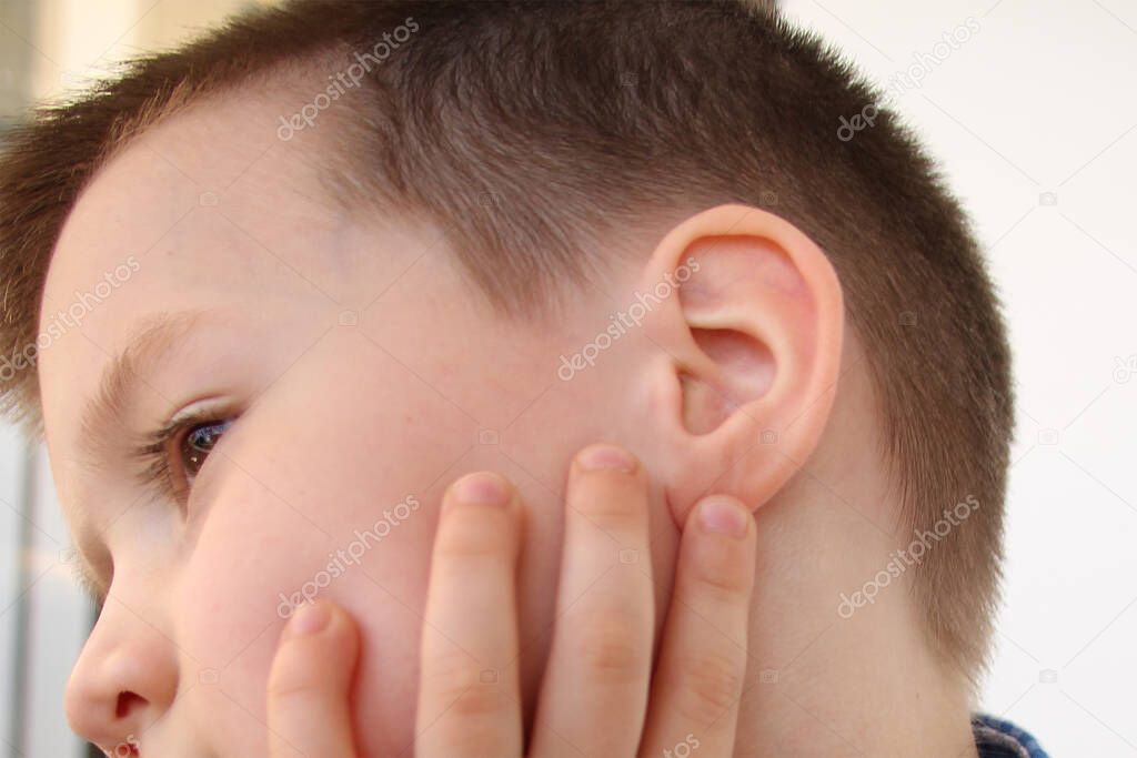 little boy holds on to the ear, part of the face close-up, medical concept, hearing control, middle ear inflammation, otitis media