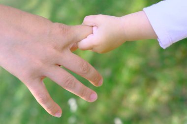 Kadın, anne küçük kızı nazikçe elinden tutuyor, yürümeyi öğretiyor, aile yaz tatili konsepti, açık hava oyunları, ilk adımlar, çocuk gelişimi.