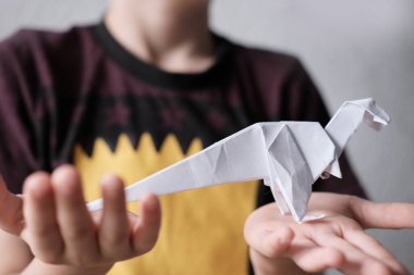 Japon origami tekniği, el sanatları, hobiler, oyunlar, odadaki aktiviteler, iyi motor becerilerin geliştirilmesi gibi konuları kullanarak beyaz kağıttan katlanmış çocuk, çocuk ve çocuk.