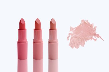 Üç tüp ruj ve soyut fırça darbesi, pembe, doğal renk lekesi, makyaj rengi eşleştirme örneği, doğal kozmetik konsepti.