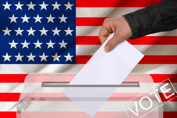男性の有権者は 米国の国旗 州の選挙の概念 国民投票を背景に 透明な投票箱に投票を落とします — ストック写真