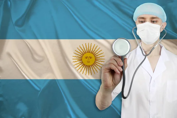 male doctor with a stethoscope against the background of the silk national flag of Argentina, concept of national medical care, health, insurance, tourism