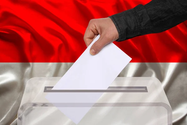男性の有権者は モナコ ニュルンベルク インドネシア 州選挙の概念 国民投票の国旗を背景に 透明な投票箱に投票を落とします — ストック写真