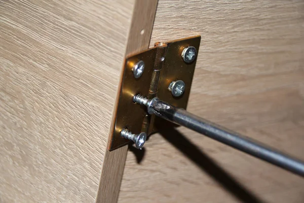 master twists the screw with a screwdriver into copper connecting loops, furniture connections, furniture assembly concept, handmade, hobby, homework