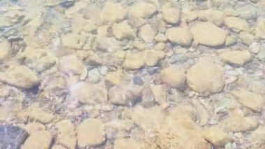 Temiz, şeffaf su göle sıçrıyor, büyük pürüzsüz taşlar su deposunun dibinde yatıyor, doğa koruma kavramı, su kaynakları.