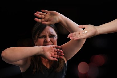 Kadın ağlıyor, elleriyle kapatıyor hapları, koruyucu el hareketleri, kadın öfke nöbeti, zihinsel bozukluk, psikiyatrik hastalık, tedaviyi reddetme