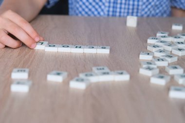 Çocuklar okul kelimesini ahşap bir masanın üzerindeki harflerle, okul yılının başlangıcı konseptiyle, ödevlerle, derslerle, okula geri dönerek oluştururlar.