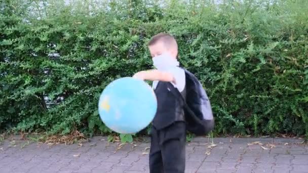 Kind Schooljongen Schoolkleren Met Een Rugzak Spelend Met Een Wereldbol — Stockvideo