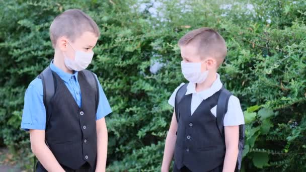 2人の男の子 顔に白い医療マスクをした子供たち 兄弟や友人 コロナウイルスの流行中に勉強するという概念 Covid 学校に戻る — ストック動画