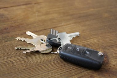 Kilitlerden ve arabadan alınan anahtarlar eski ahşap bir masanın üzerinde, doğal dokular, keşif konsepti, sırlar, ipuçları, gayrimenkul, evler, apartmanlar, ipotekler, konut kredileri, arabalar.