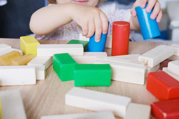 kid, baby builds towers and buildings from colored wooden figures, the concept of housing construction, mortgage, insurance, happy childhood, children\'s games, alpha generation