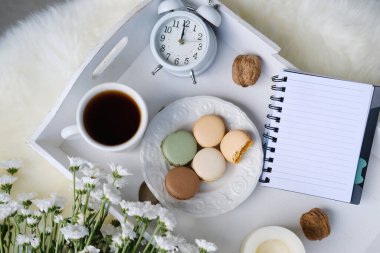 Siyah çay, kahve, badem kurabiyeli tabak, çiçekler, mumlar, yazı için boş çarşaflı not defteri, konsept yaşam tarzı, hayatın keyfi, üst görünüm